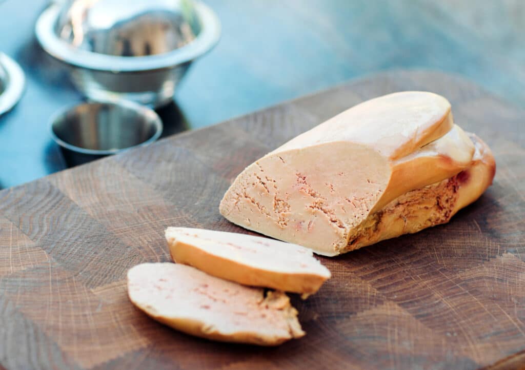 Foie gras d’oie présenté sur une planche de bois avec une texture fondante et une couleur dorée