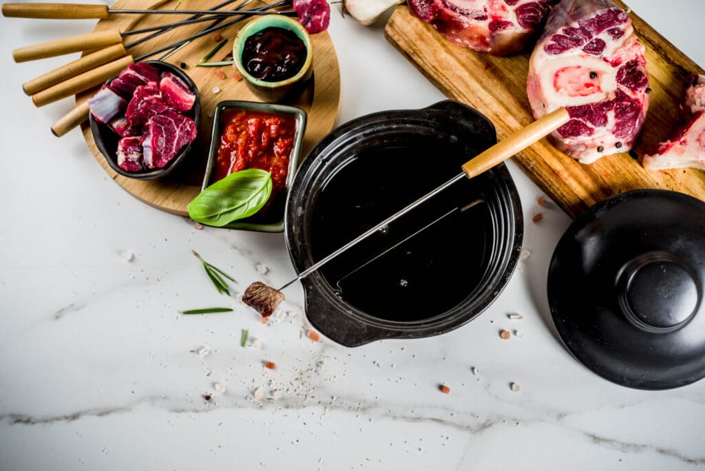 Fondue bourguignonne avec morceaux de viande à cuire dans l’huile chaude.